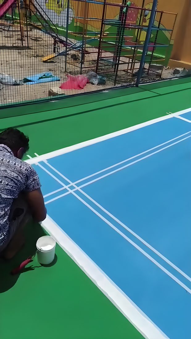 Line markings being hand-painted at a school court with the playground behind