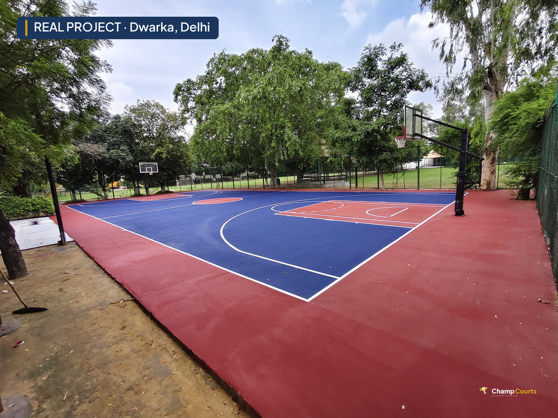 Finished 8-layer acrylic basketball court at St Mary's School, Dwarka, daylight view of the blue and red court with hoop and campus trees