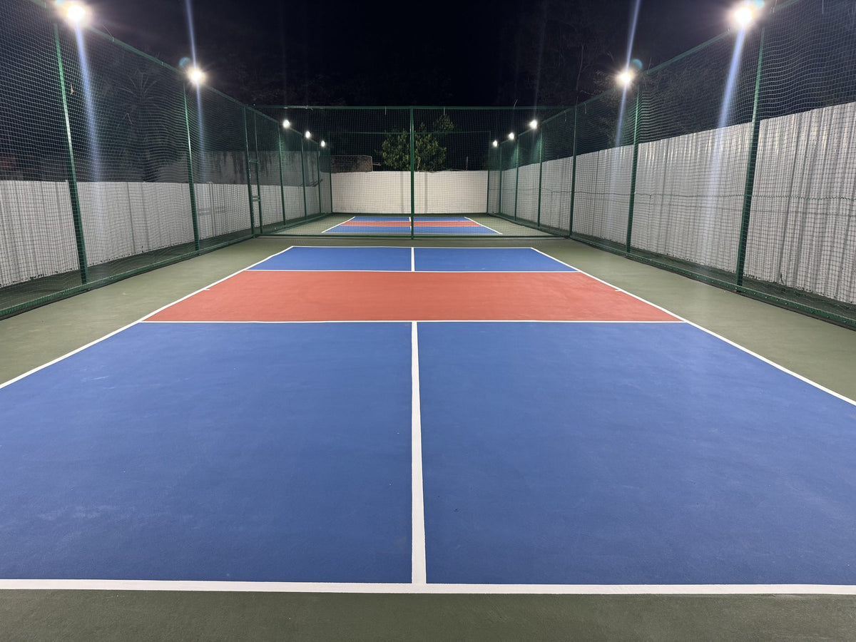 Floodlit twin acrylic pickleball courts inside an enclosed arena in Sivakasi, Tamil Nadu