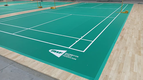 BWF-grade PVC badminton court mat installed over a sprung wooden subfloor