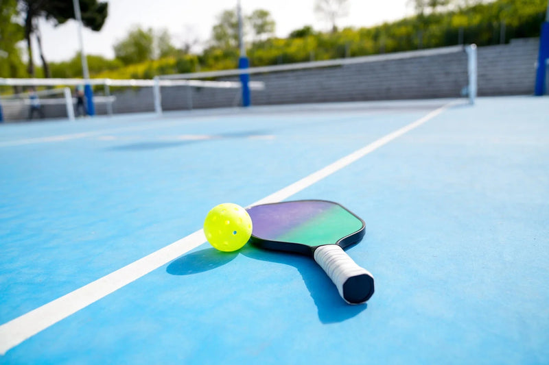 Pickleball paddle and ball on acrylic court surface