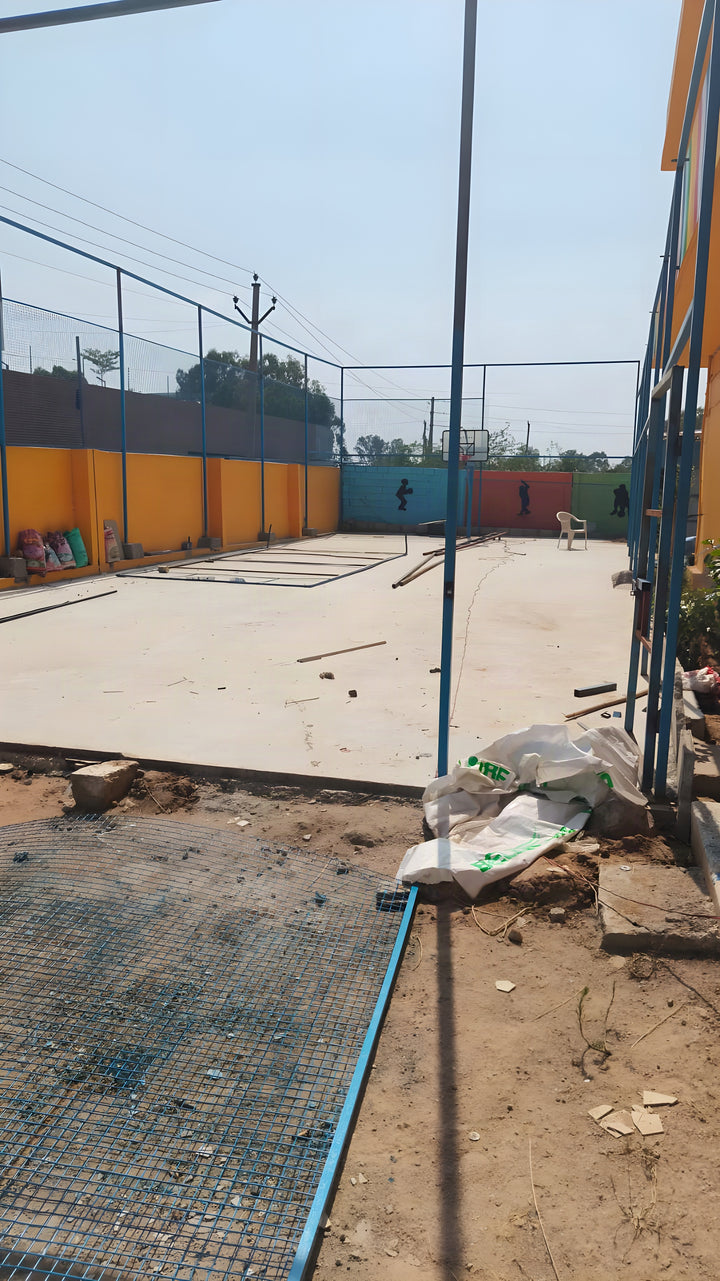 Concrete base work inside the fenced court enclosure at a school site — ChampCourts project, Hyderabad