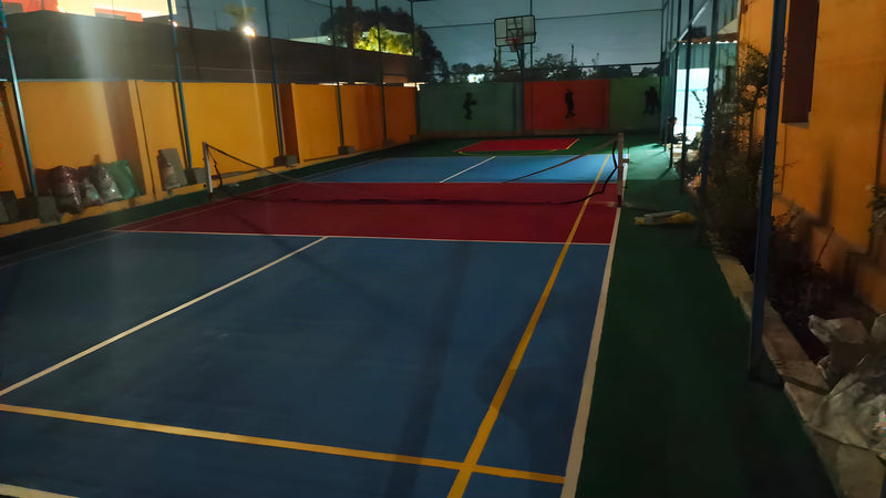 Floodlit multi-sport acrylic court with badminton net at night — ChampCourts project, Hyderabad