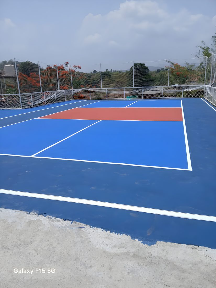 Rooftop pickleball court with safety netting overlooking hills, Maharashtra