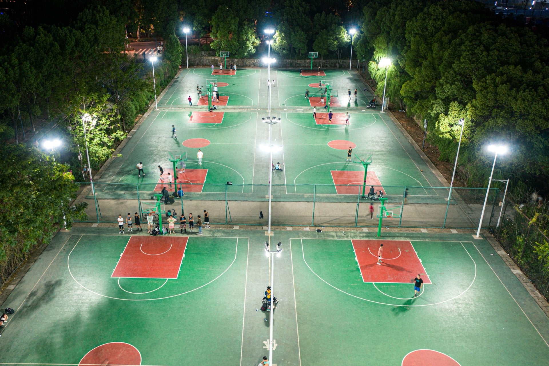 Acrylic basketball court fully illuminated by LED floodlights at night, Noida residential society