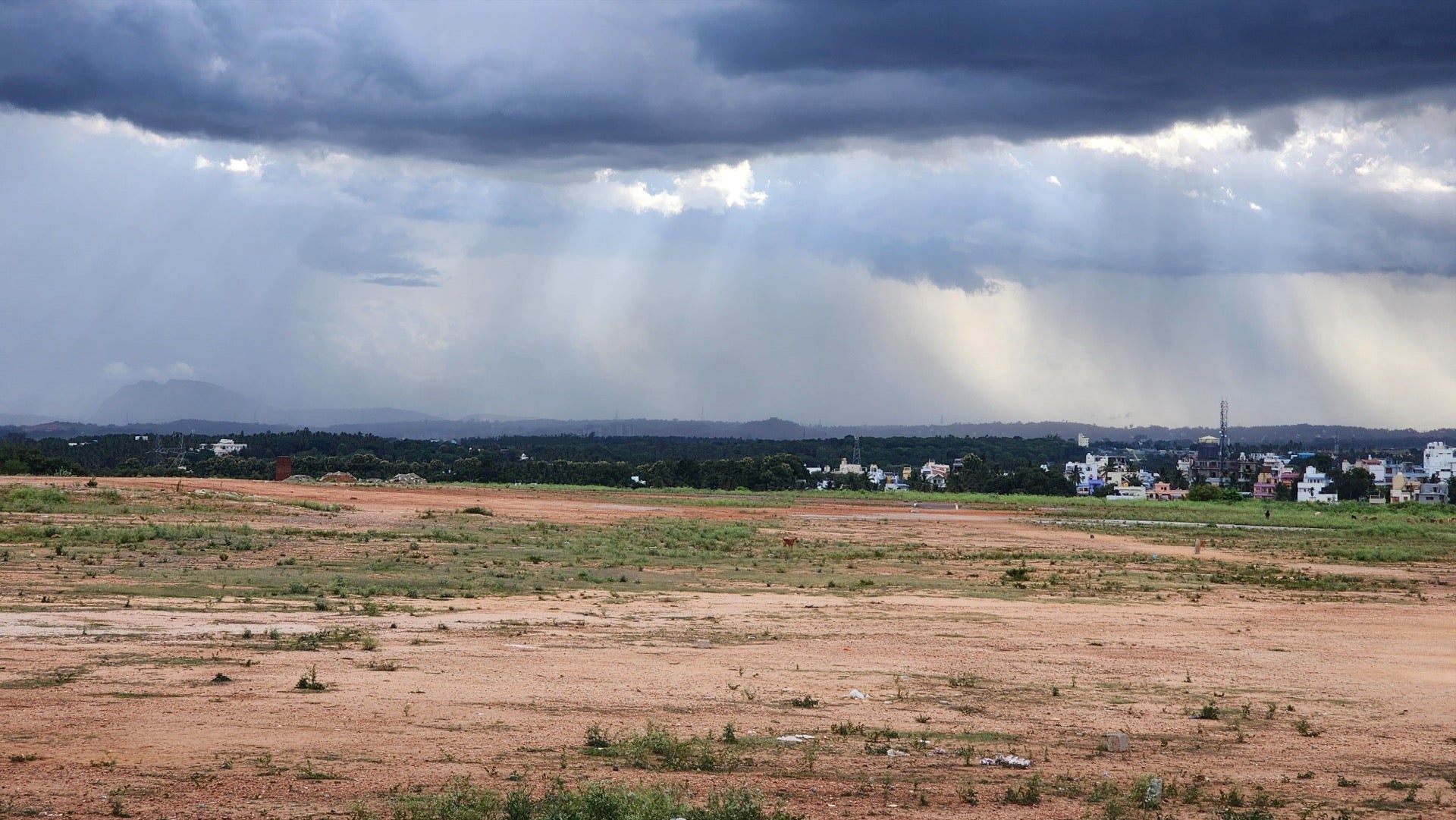 Dark monsoon clouds gathering over the Tezpur school site before construction